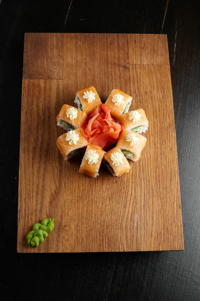 Koyu arka plan üzerinde ahşap bir gemide suşi roll