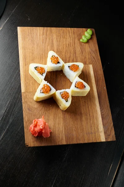 Koyu arka plan üzerinde ahşap bir gemide suşi roll