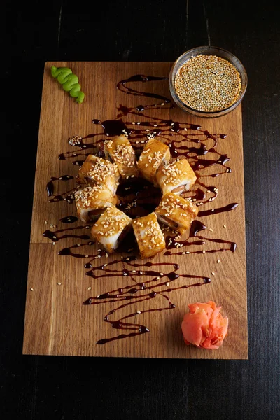 Koyu arka plan üzerinde ahşap bir gemide suşi roll