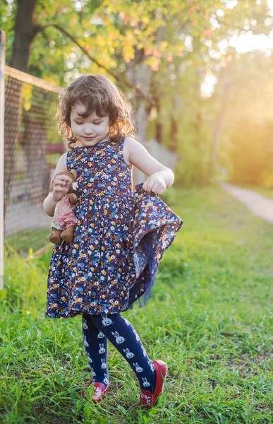 Liten lockigt flicka med en nalle i handen — Stockfoto