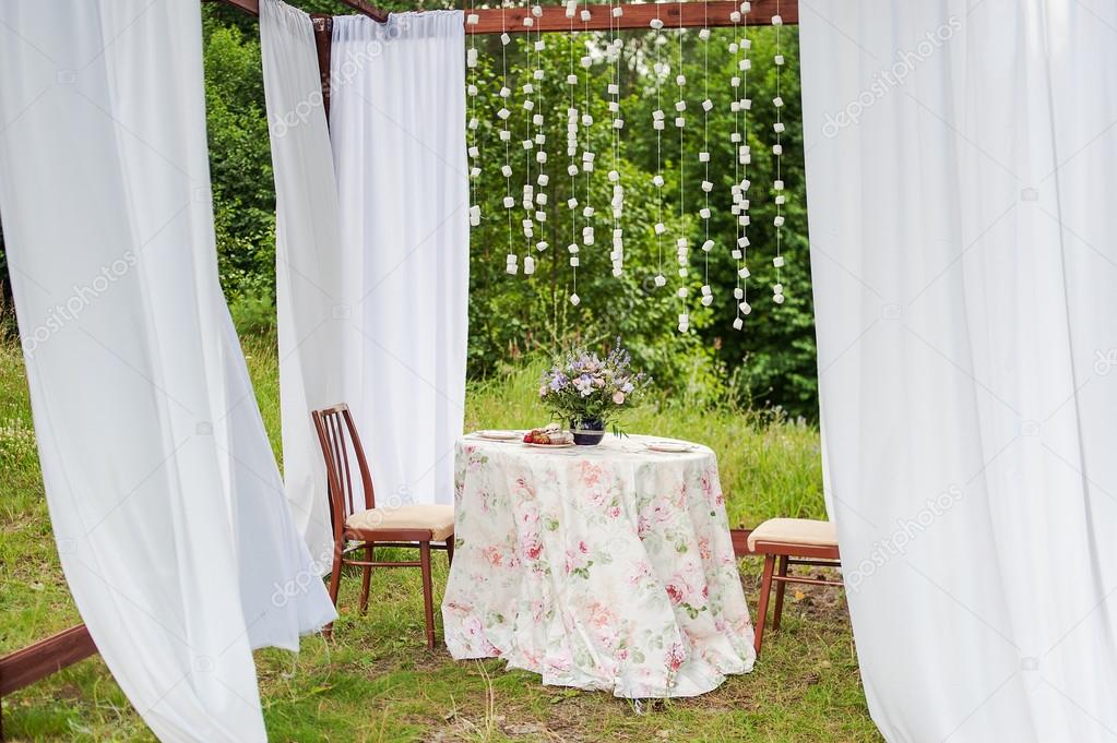 Outdoor gazebo with white curtains. Wedding decorations.
