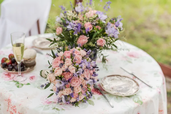 屋外にテーブルを用意しています。ラベンダーとバラのフラワーアレンジメント。結婚式の装飾. — ストック写真