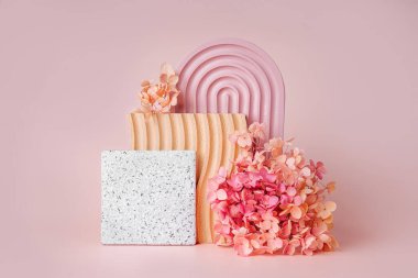 Pembe kemer, dalgalı ahşap tabak ve pembe arka planda taş kaplama çiçekler. Çeşitli materyal ve geometrik şekillere sahip stil arkaplanı