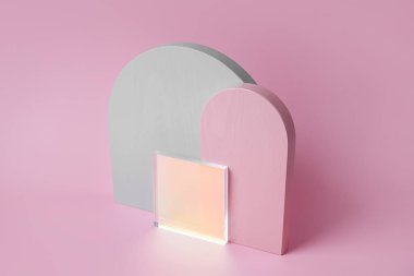 Pembe arka planda gri ve pembe kemerler ve parlak akrilik plaka. Çeşitli materyal ve geometrik şekillere sahip stil arkaplanı