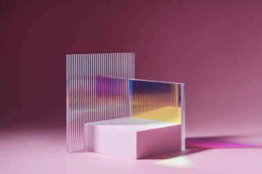 Geometrik şekiller ürün gösterimi için podyum oluşturur. Pembe arka planda parlak akrilik çarşaflı tek renkli platform. Sunum için şık bir zemin. Asgari biçim.