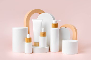 Podyumlar ve geometrik formlar üzerine çeşitli boş kozmetik kaplar. Marka ve ambalaj sunumu için arka plan. Doğal cilt bakım ürünü.