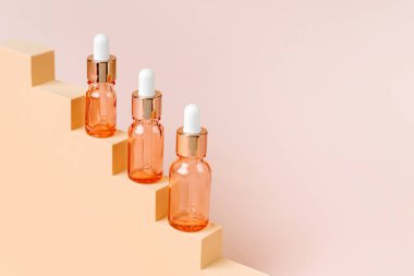 Bej merdivenlerde gül rengi cam damlalar. Marka ve ambalaj sunumu için arka plan. Doğal cilt bakım ürünü konsepti.