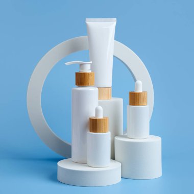 Podyumlar ve geometrik formlar üzerine çeşitli boş kozmetik kaplar. Marka ve ambalaj sunumu için arka plan. Doğal cilt bakım ürünü.