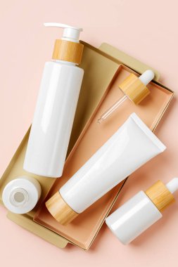 Pompa şişesi, krem tüpü ve pastel arka planda damlatıcı. Kozmetik konteynır modelleri. Marka ve ambalaj sunumu için arka plan. Doğal cilt bakım ürünü konsepti.