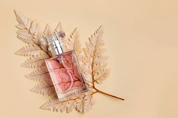 Perfume Bottle with autumn leaf on pastel background. Beauty concept
