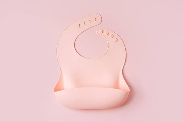 Pink silicone baby bib. First baby accessories for dinner. Top view, flat lay
