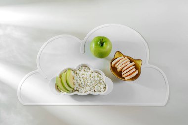 Çocuk Kahvaltısı. Kır peyniri, böğürtlen, elma ve abur cubur kaplı bir bulut şeklinde tabak. Çocuklar için yemek fikri.