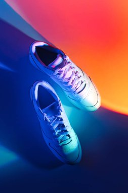 Canlı soyut arka planda moda spor ayakkabıları. Neon ışıklı spor ayakkabılar. Mavi ve turuncu gradyan.  