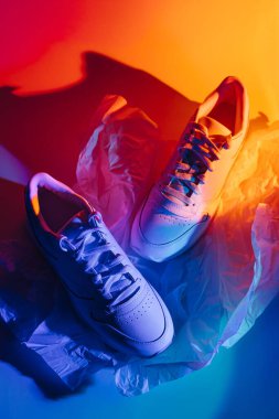 Canlı soyut arka planda moda spor ayakkabıları. Neon ışıklı spor ayakkabılar. Mavi ve turuncu gradyan.  