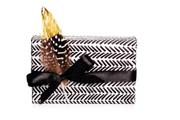 Målade papper närvarande wrap med svart band bow och guld fjäder på vit bakgrund — Stockfoto