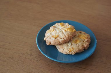 İki kepekli kurabiye üst üste küçük siyah ve mavi bir seramik tabakta ahşap bir masa arkasında, yemek, atıştırmalık, tatlı, kopyalama alanı üzerinde üst üste yığılır.