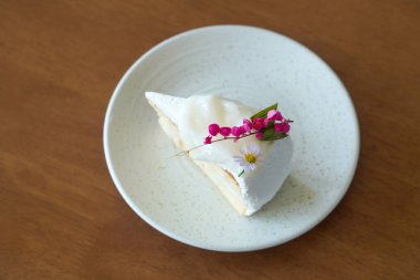 Hindistan cevizi kremalı pasta, beyaz seramik kapta pembe ve mor çiçekler ahşap arka planda, tatlı, yemek, moda, dekor, kopyalama alanı