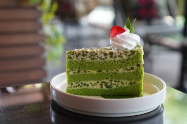 Yan manzara yeşil ve beyaz Singapur Lod Chong Keki. Krem şanti ile süslenmiş. ve muz yapraklarına gül yaprakları, beyaz seramik bir tabağa, ve kırmızı ve beyaz bir bez üzerine, yiyecek, kopyalama alanı