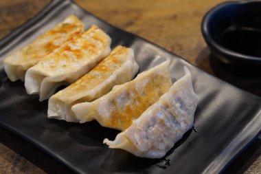 Yakın plan sıcak beş parça gyoza siyah seramik tabak ve sos içinde siyah seramik bardak ahşap zemin zemin zemin, yiyecek, atıştırmalık, kopyalama alanı