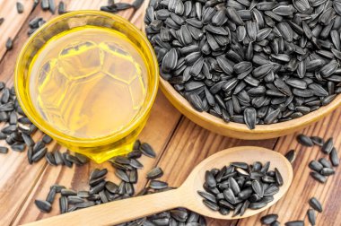 Tahta kase ve kaşık, ayçiçeği tohumları ve cam içinde pişirme yağı..