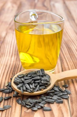 Cam bardakta pişmiş yağ ve ahşap masada ayçiçeği tohumları olan tahta kaşık. Kapat..