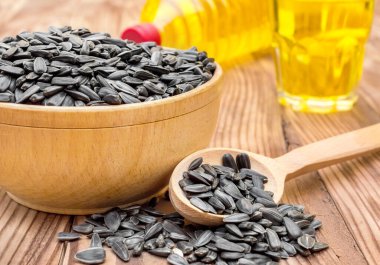 Tahta kase ve kaşık, ayçiçeği tohumları ve cam içinde pişirme yağı..