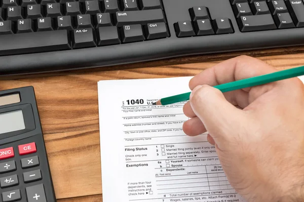 Man\'s hand filing tax form at the workplace.