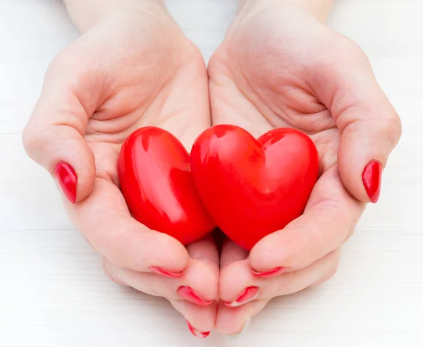 Las Manos Una Joven Sostienen Dos Corazones Rojos Cerca — Foto de Stock