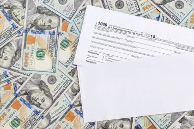 Dolar banknotlarının arka planında vergi formu olan zarf. Üst görünüm.