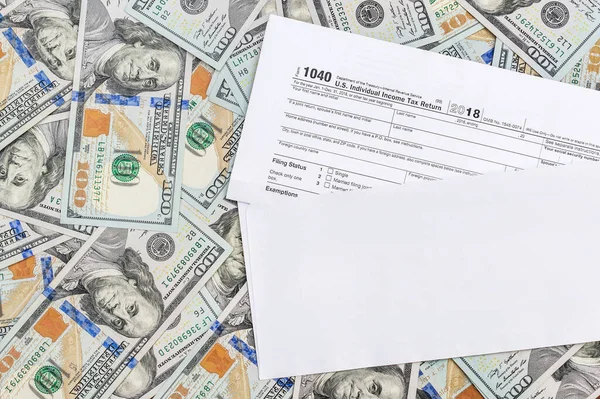 Dolar banknotlarının arka planında vergi formu olan zarf. Üst görünüm.