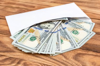Tahta arka planda beyaz zarf içinde dolar banknotları. 