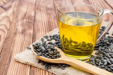 Cam bardakta pişmiş yağ ve çuval bezinde ayçiçeği tohumları olan ahşap kaşık. Kapat..