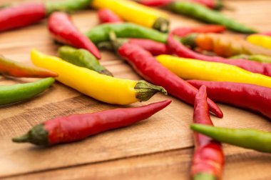 Ahşap arka planda küçük renkli kırmızı biber yığını.