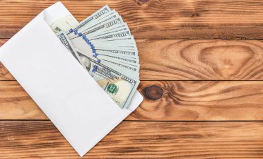 Tahta arka planda beyaz zarf içinde dolar banknotları. Üst Manzara. Metin için boşluk.