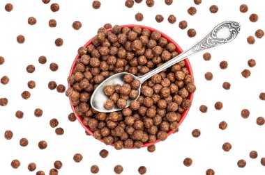 Çikolatalı mısır topları ve beyaz kaşıkla kırmızı kase. Üst görünüm.