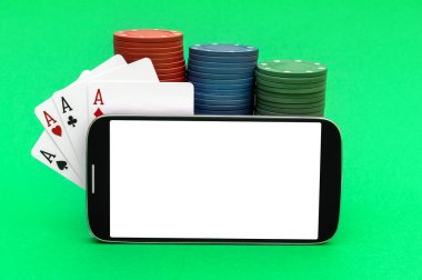 Boş ekranlı akıllı telefon, poker fişleri ve yeşil arka planda iskambil kartları. Çevrimiçi poker. Metin için boşluk.