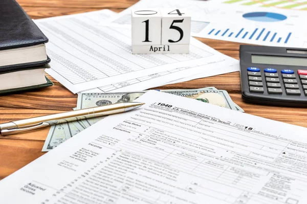 Pay tax concept. Office desk with tax forms, documents with financial, money and cubes with date of 15 april.