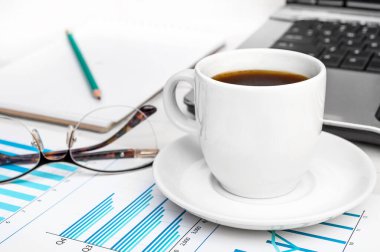 İş yerindeki bilgisayarlı ve grafikli bir fincan kahve..