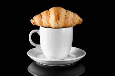 Bir fincan kahve ve kruvasan siyah yansıtıcı arka plan..