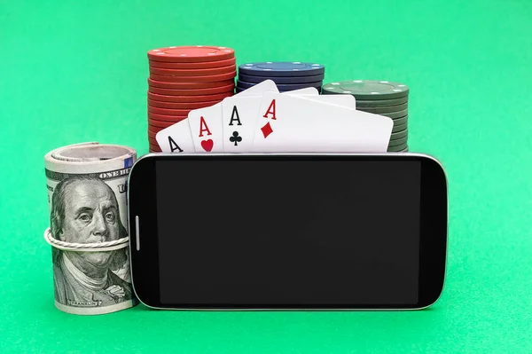 Smartphone with blank screen, poker chips, playing cards and money on green background. Online casino. Space for text.