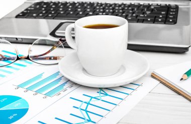 İş yerindeki bilgisayarlı ve grafikli bir fincan kahve..