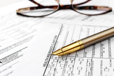 Pen with eyeglasses on health insurance claim form.