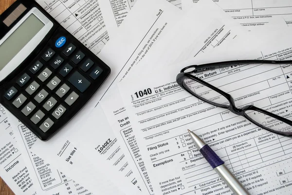 Pluma, gafas y calculadora en el formulario de impuestos — Foto de Stock