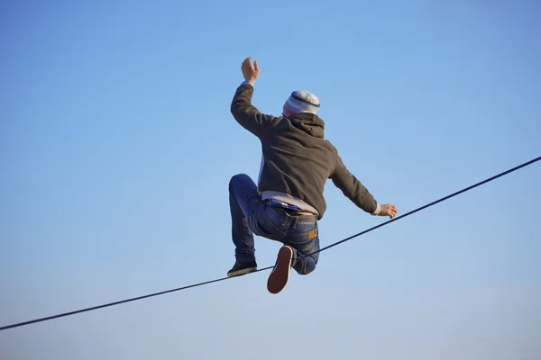 Парень, сидящий на Slackline — стоковое фото