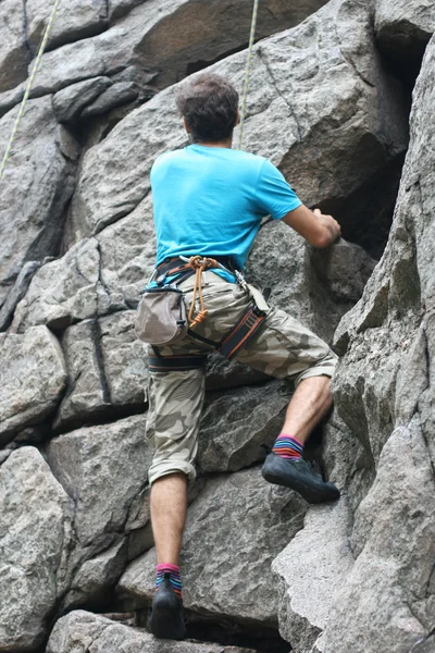 Bergsteigermädchen mit rotem Hut klettert auf Felsen — Stockfoto