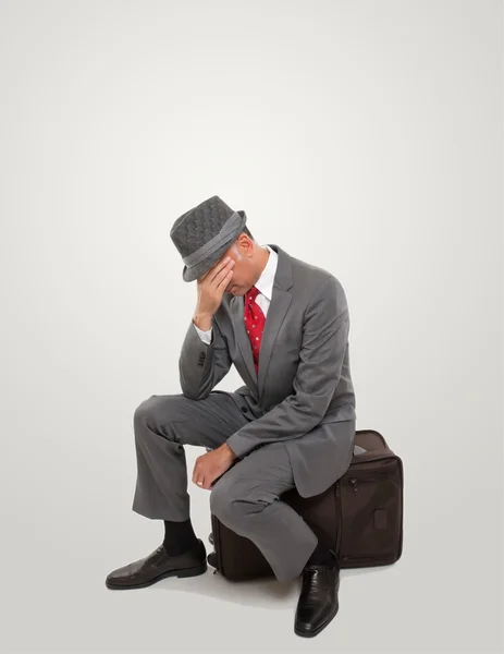A frustrated business traveler seating on a suitcase — Stock Photo, Image