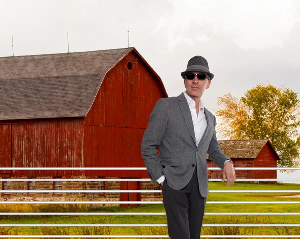 Homem na moda de pé de um celeiro vermelho — Fotografia de Stock