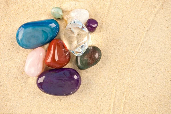 Коллекция красивых драгоценных камней, лежащих на песке — стоковое фото