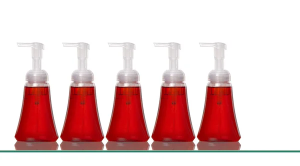Diverse bottiglie di sapone per le mani in plastica su uno scaffale di vetro — Foto Stock