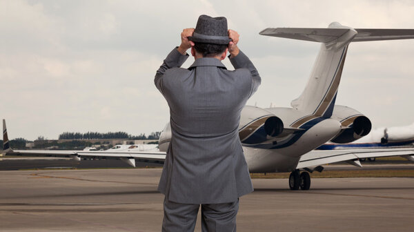 Business man holding his hat at a windy airport